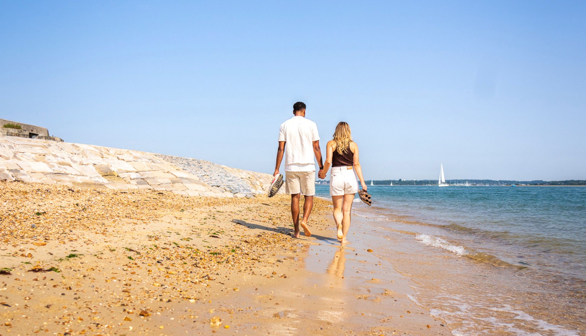 Couple walking in Calshot Beach in Hampshire Couple walking in Calshot Beach in Hampshire