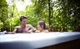 A couple enjoying a hotub on the balcony of their cabin at Blackwood Forest in Hampshire